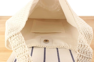 Detail view of woven shoulder bag featuring fabric lining and silver magnetic snap closure