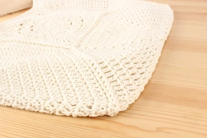 Close-up of handmade cream crochet shoulder bag showing intricate geometric knit patterns