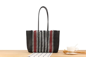 Detail shot of tricolor woven tote bag texture on a minimalist wooden table