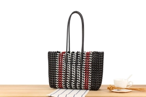 Detail of eco-friendly woven tote bag with red and black stripes on a wooden table