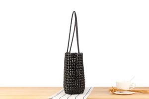 Detail of black woven tote bag with diamond pattern on blue striped tablecloth