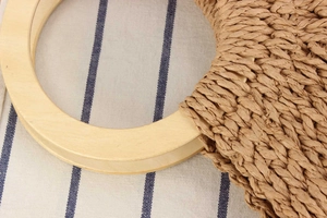 Detail der handgeflochtenen Papierschnur-Textur und des runden Holzgriffs der Strandtasche
