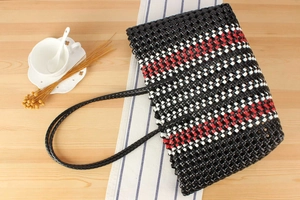 Detailed view of handmade woven basket with red and black pattern on wooden table