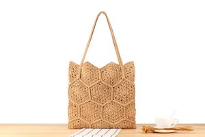 Detail of handmade crochet tote bag featuring a geometric honeycomb texture on wood