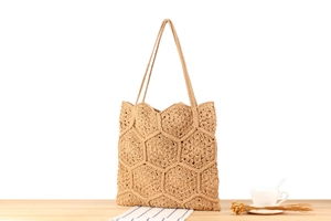 Detailed view of handmade beige crochet tote bag with floral patterns on a wooden surface
