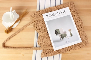 Close-up of handmade crochet tote bag with floral knit patterns on a rustic table