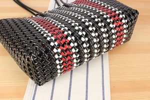 Detailed close-up of the geometric black, white and red woven pattern on a hand-knit bag