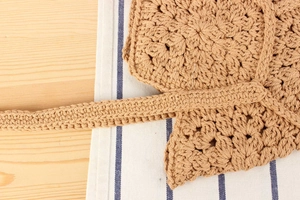 Detailed view of handmade khaki crochet woven bag with intricate floral stitch patterns