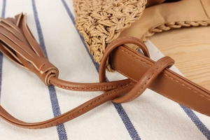Detailed macro view of woven straw texture with brown leather strap and tassel decoration