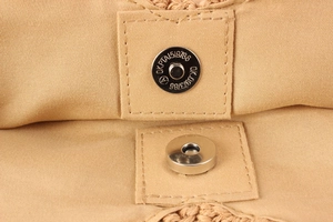 Macro detail of silver magnetic snap closure on handmade woven bag with canvas lining