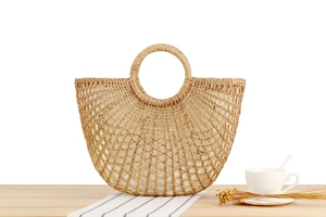 Detail der handgefertigten halbrunden Strohtasche mit Ringgriff und geflochtenem Netz