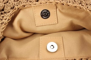 Detailed close-up of woven bag interior with brown fabric lining and magnetic snap closure