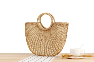 Detailansicht der hohlen Stroh-Handtasche mit Baumwollfutter auf einem Holztisch