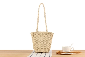 Close-up of handmade straw tote bag featuring thick woven texture and braided shoulder straps