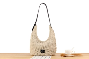 Detail of hand-woven beige hobo bag featuring hollow mesh and adjustable leather strap
