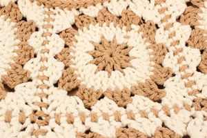 Macro detail of hand-crocheted cotton bag with ivory and khaki floral knit pattern