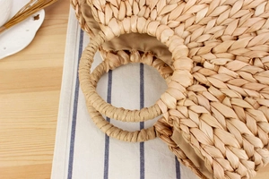 Gros plan d'un sac en paille tressée main avec poignées rondes et doublure interne