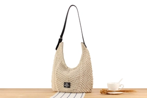 Close-up of beige crochet hobo bag with black leather strap and square woven logo patch