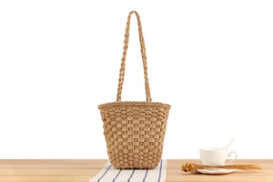Detail of hand-woven straw tote bag on a wooden table with natural fiber texture