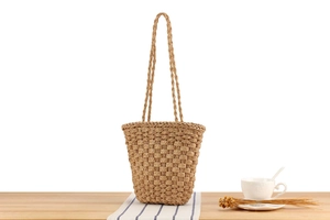Detail of hand-woven straw tote bag texture and straps on wooden table with decor