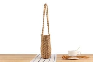 Detail of handmade woven water bottle bag with natural fiber texture and long strap