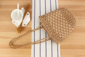 Detail shot of a handmade straw tote bag with woven texture on a wooden table