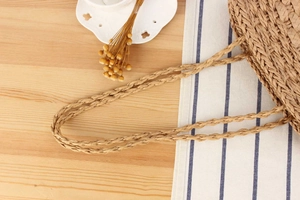 Close-up of handmade straw bag showing woven handle detail and natural fiber texture
