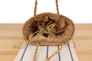 Top view detail of handmade straw woven bag showing drawstring lining and oval base