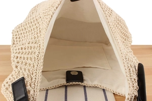 Detail of hand-woven straw bag with canvas lining, magnetic clasp and black leather accents
