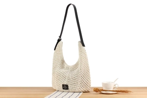 Detail of hollow woven beige bag with black leather strap and chic brand logo label