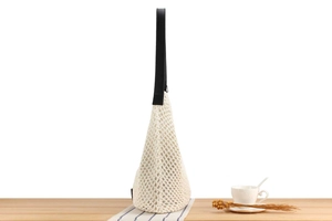 Detailed weave of cream cotton mesh tote bag with black faux leather shoulder strap