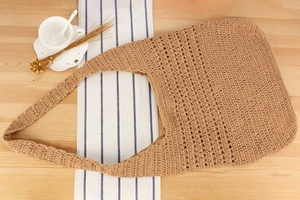 Gros plan détaillé du motif ajouré tissé sur un sac à bandoulière en paille marron