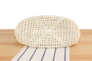 Detail of hand-woven cream beige crochet pattern on a wooden table with striped fabric