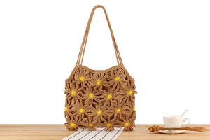 Close-up of handmade crochet daisy pattern on brown woven bag with yellow flower centers