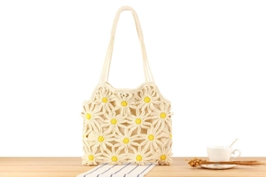 Close-up of handmade crochet tote bag with yellow daisy patterns on a wooden table