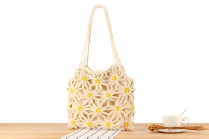 Detailed close-up of handmade crochet tote bag featuring white hollow daisy floral patterns
