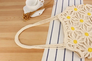 Detailed close-up of handmade woven cotton crochet tote bag with white daisy patterns