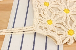 Detailed close-up of handmade crochet daisy pattern and woven cotton rope straps on bag