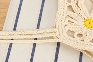 Detail of hand-woven cotton crochet bag featuring yellow daisy pattern and sturdy straps