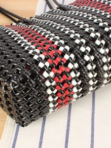 Handwoven basket bag with black red and white checkered pattern in close-up view