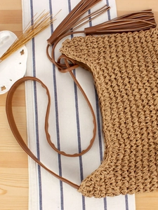 Handmade woven straw shoulder bag with long side tassels and brown leather straps