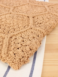 Handmade crochet woven bag with honeycomb pattern on a natural wood and striped background