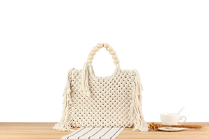 Detailed macro of handmade cotton rope woven bag with wooden beads and long fringe tassels
