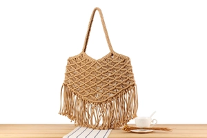 Detail of bohemian macrame woven cotton rope tote bag with fringe accents