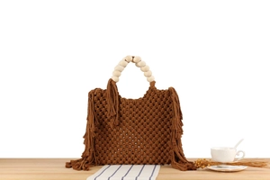 Detail of bohemian dark brown woven tote with tassel fringes and wooden bead handles