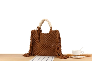 Detail of bohemian cotton rope woven handbag featuring wood bead handle and long tassels