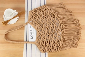 Top view of bohemian cotton rope woven bag with fringe tassels on rustic wooden desk