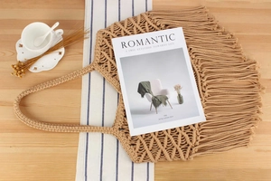 Close-up of handmade macrame cotton rope tote bag with long bohemian tassels on wood