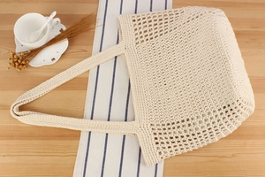 Detailed close-up of cream handmade crochet tote bag featuring intricate hollow mesh patterns