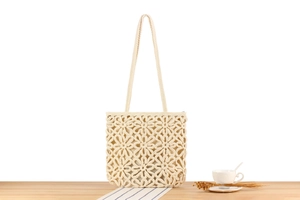 Détail des motifs de fleurs tissés sur le sac en coton beige ajouré et élégant
